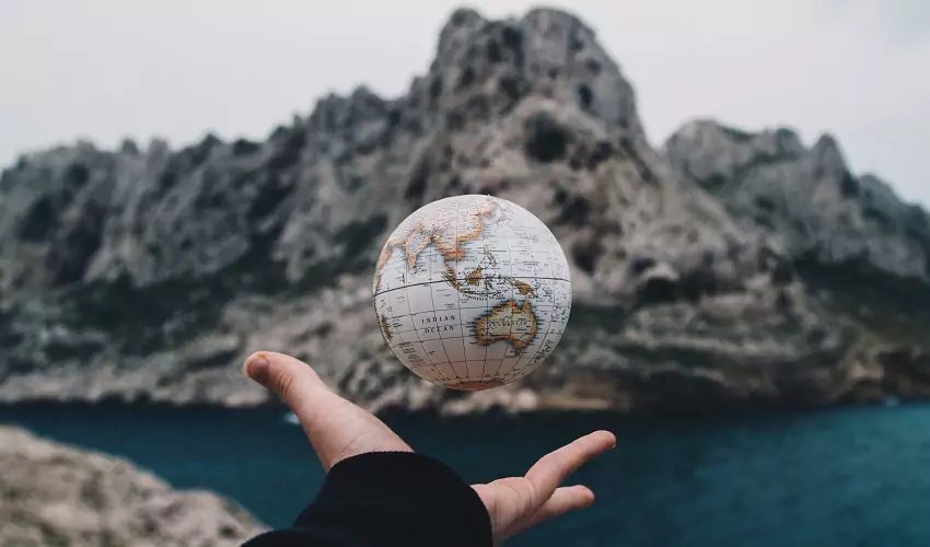 Person's hand holding a globe
