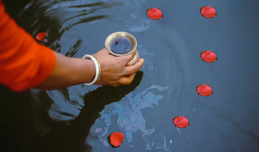 Hand holding water ceremony offering cup